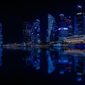 A city skyline at night with lights reflecting on the water.