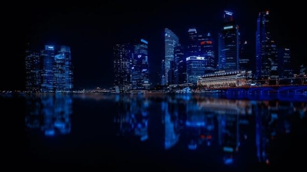 A city skyline at night with lights reflecting on the water.