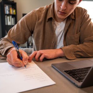 A person writing on paper with a pen.