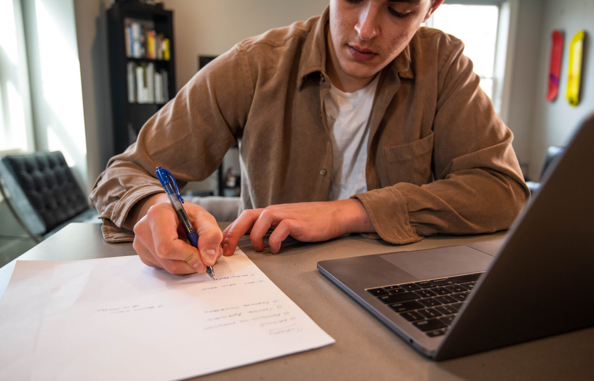 A person writing on paper with a pen.