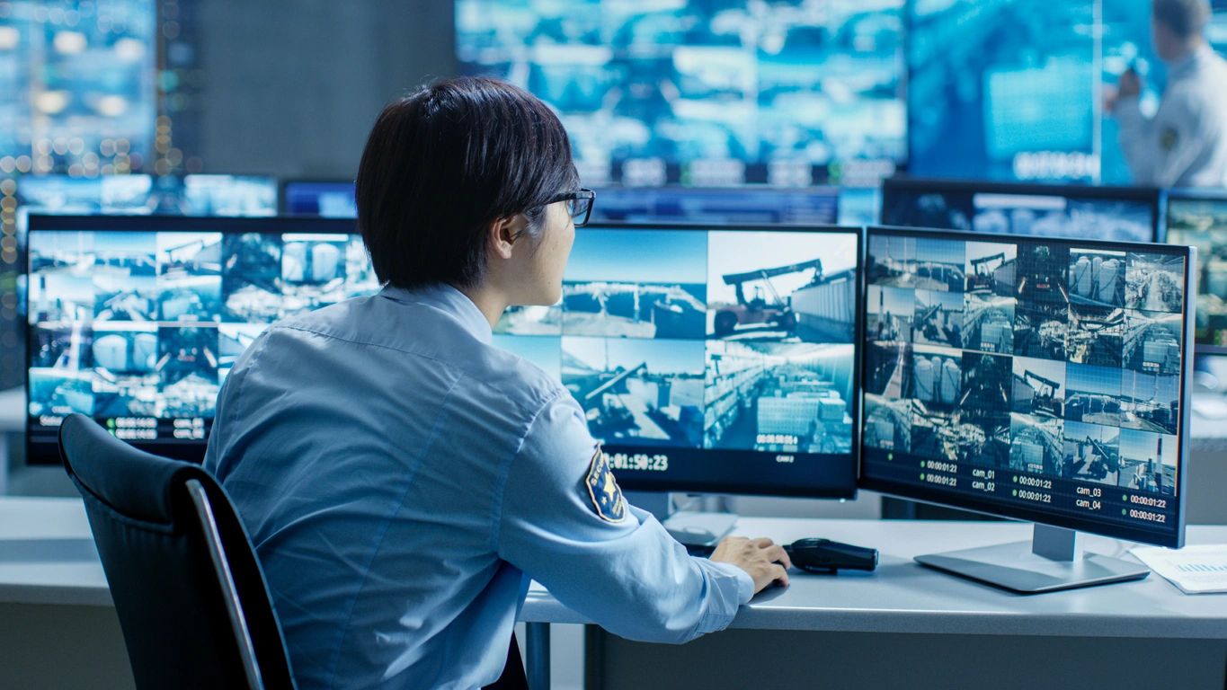 A man sitting at his desk in front of multiple monitors.