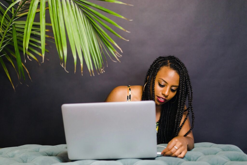 A woman with long hair is looking at her laptop.