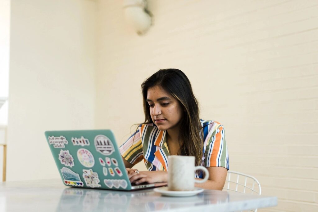 A woman sitting at a table with her laptop.