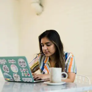 A woman sitting at a table with her laptop.